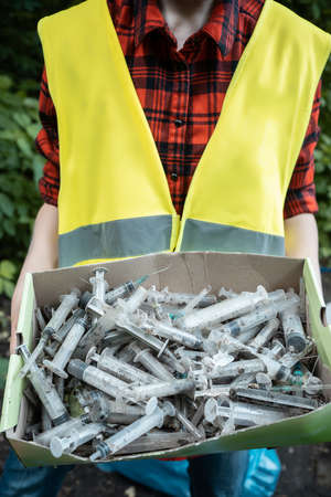 volunteer cleaning up park from used syringe by drug addicted junkiesの写真素材