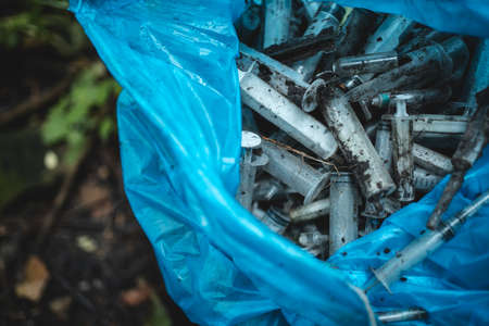 garbage bag with used disposable medical syringe leaved by drug addicted in parkの写真素材