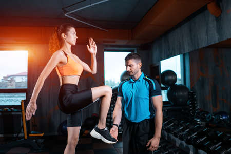 athlete female has exercising lunges on step box with personal trainer in gymの写真素材
