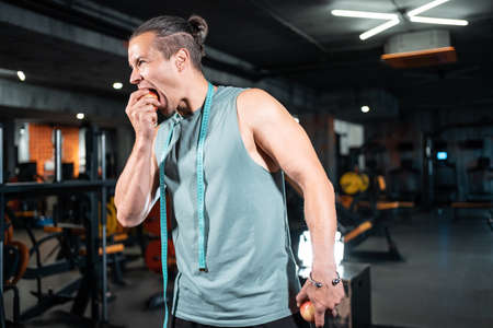 young handsome athlete hungry and eating healthy apple fruit in gymの写真素材