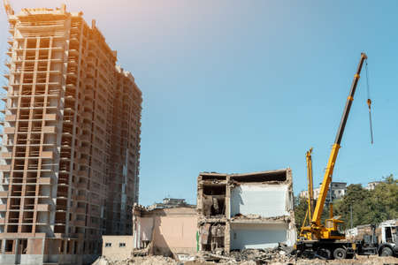 crane and demolition of old building near new construction of modern skyscraperの写真素材