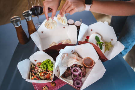 food delivery or cardboard takeaway boxes with salad, meat, dumplings or dessertの写真素材