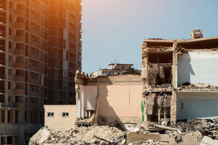 demolition of old building near new construction of modern skyscraperの写真素材