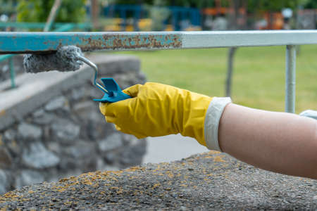 volunteer worker painting with brush or roller and renovate railing or fenceの写真素材