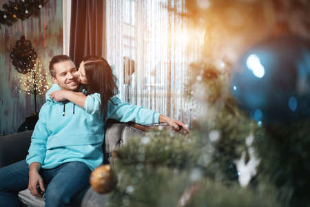 young happy couple in love, hugging near christmas tree at cozy homeの写真素材