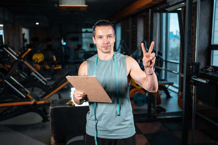young attractive man personal trainer planning workout with clipboard in gymの写真素材