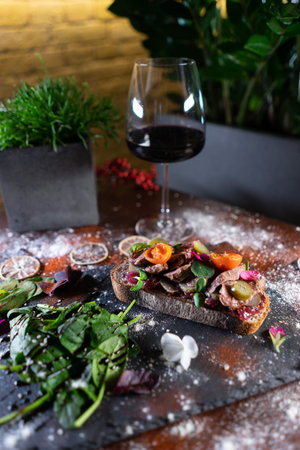fresh crusty sandwich with roast beef, vegetables, tomato, cucumber and wine