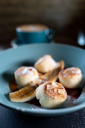 fresh coffee and cheese pancakes with banana, mango and berry sauceの写真素材