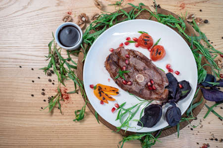 top view of grilled ribeye beef steak with spice, herb and sauce on white plateの写真素材