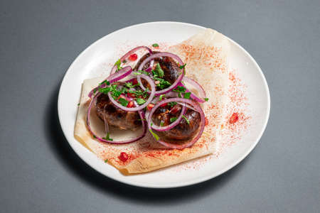 georgian fried pork sausages kupaty with onion, cilantro on pita on white plateの写真素材