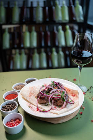 georgian fried pork sausages kupaty with onion, cilantro on pita on white plateの写真素材