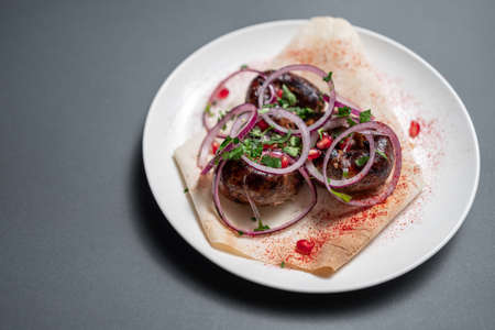 georgian fried pork sausages kupaty with onion, cilantro on pita on white plateの写真素材