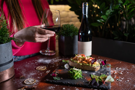 person eats fresh sandwich with avocado, red salmon fried fish, seaweed, wineの写真素材