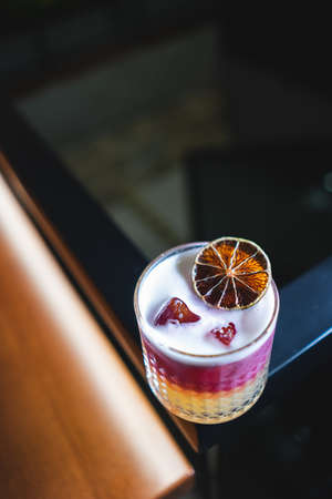 fresh stylish layered pink sour grapefruit cocktail with foam and iceの写真素材
