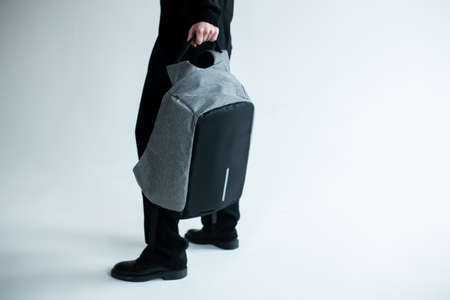stylish hipster person holding modern backpack bag on white backgroundの写真素材