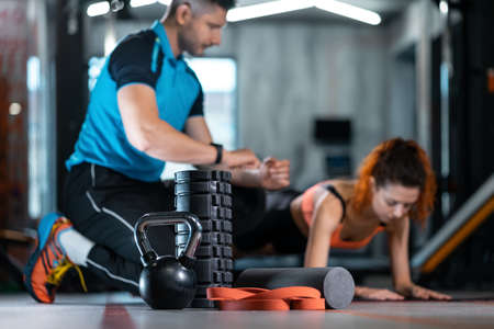 fitness female exercising plank with personal trainer with equipment in gymの写真素材
