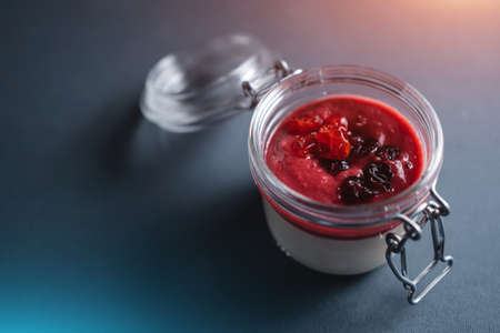 berry panna cotta dessert with cherry sauce in glass jar on black backgroundの写真素材