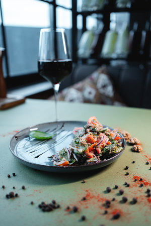 georgian salad with tomato, cucumber or walnut and red wine in glass on tableの写真素材