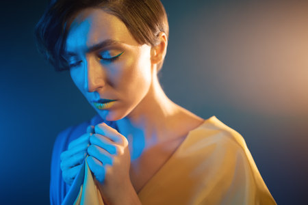 young ukrainian woman in yellow and blue clothes and dress praying for ukraineの写真素材