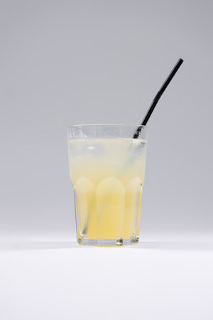 fresh cold fruit yellow drink with ginger lemonade, ice, straw isolatedの写真素材