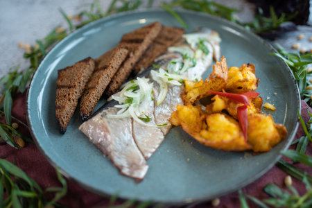 fresh marinated herring fish with potato and brown bread and onion in restaurantの写真素材