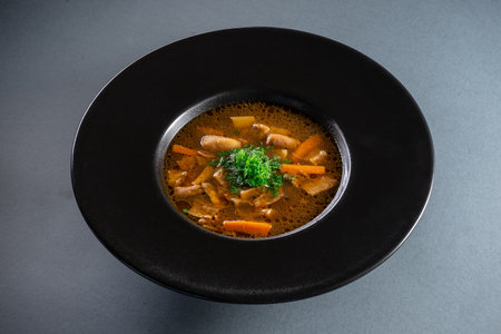 black plate with brown soup pottage with mushroom, carrot, vegetables, dillの写真素材