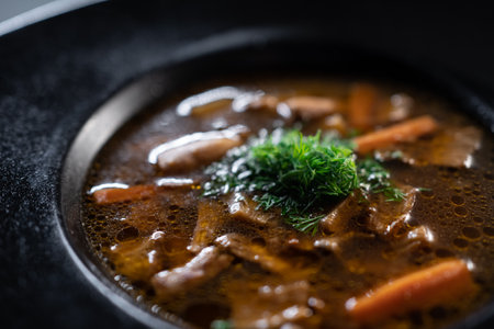 black plate with brown soup pottage with mushroom, carrot, vegetables, dillの写真素材