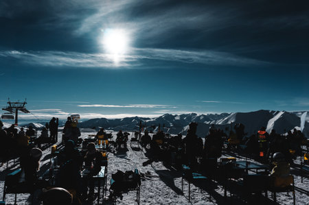 happy skiers have rest, eating in open air restaurant on ski slope mountainの写真素材