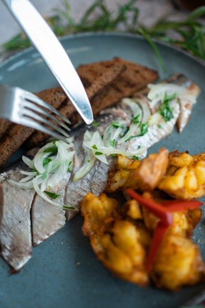 fresh marinated herring fish with potato and brown bread and onion in restaurantの写真素材