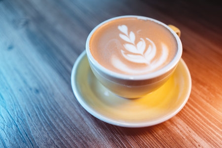 fresh tasty cappuccino or latte coffee with milky foam on wooden table in cafeの写真素材