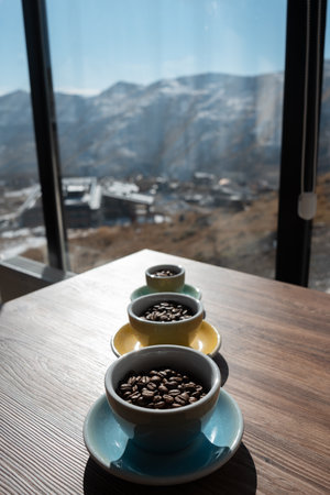 three cups with brown coffee beans on wooden tableの写真素材