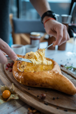 person mixing suluguni cheese and egg yolk in georgian adjarian khachapuriの写真素材