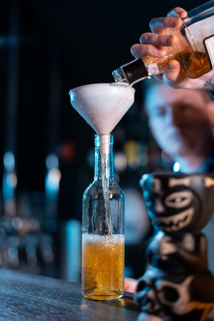 bartender hand pouring yellow whiskey to bottleの写真素材