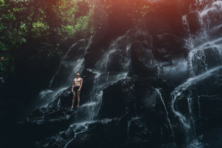 male standing at waterfall in Bali indonesiaの写真素材