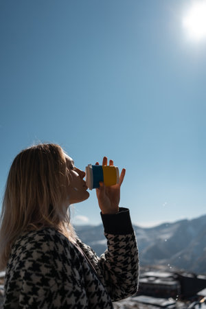Ukrainian female drink hot coffee drink from disposable cup at nature, mountainsの写真素材