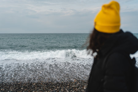 female tourist in yellow hat on seaside watching on ocean or horizon outdoorsの写真素材