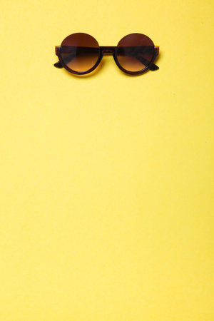 luxury fashionable sunglasses lying on yellow background, flatlay top viewの写真素材