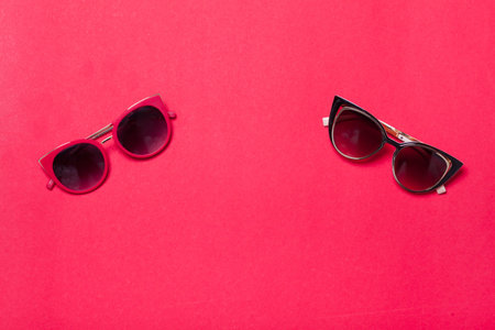 luxury fashionable sunglasses lying on red or pink background, flatlay top view