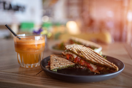 toasted vegetarian sandwich with mozzarella cheese and tomato and orange juiceの写真素材