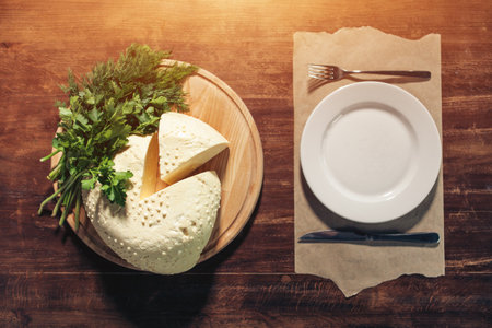 yellow suluguni cheese with parsley and dill on wooden table, flatlay top viewの写真素材