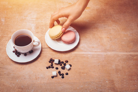 person drink fresh espresso coffee with macaroons on wooden backgroundの写真素材