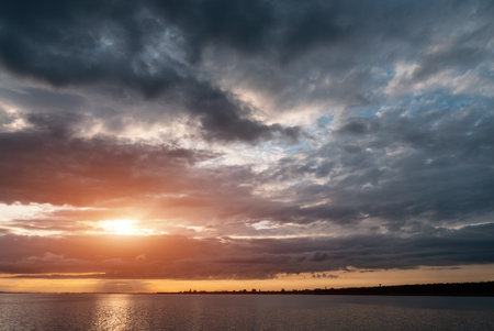 beautiful sunset over sea with dramatic clouds and orange sun lightの写真素材