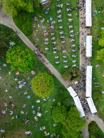 city street food festival event at green park at summer, tents of food market at green meadow, crowd walking and sitting at picnic, aerial viewの写真素材