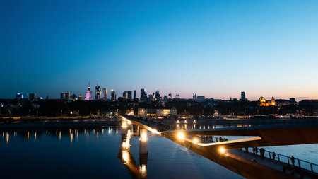 newly built pedestrian and bicycle modern bridge over Vistula river at night, illuminated contemporary architecture of Warsaw, aerial top viewの写真素材