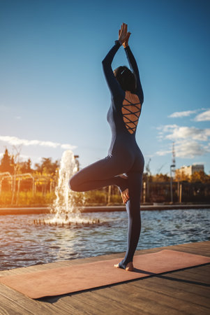 young woman practicing yoga at sunset outdoors, body conscious person exercising stretching and relaxation asana, balance and harmony conceptの写真素材