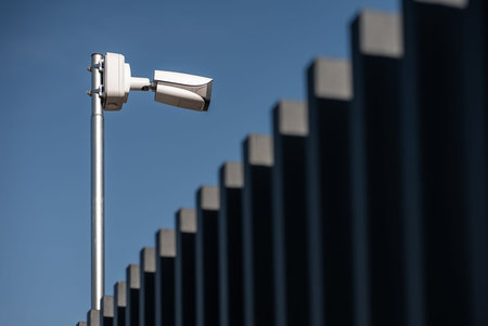 Security cameras mounted on pole monitoring surroundings in clear blue sky, video surveillance in...