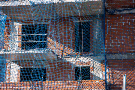 Construction site with scaffolding and protective netting on multi-story building under development...