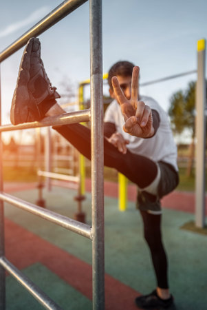 young athletic man exercising at fitness calisthenics workout and stretching legs at street gym...