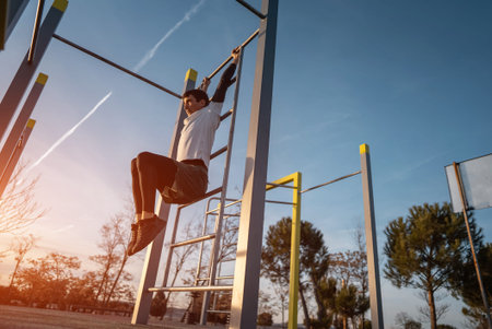 young athletic man exercising fitness calisthenics workout and making hanging leg raises for abdomen...