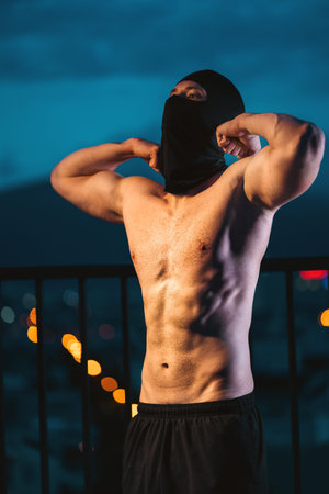 Muscular athlete with mask posing powerfully at night, showcasing strength and mystery, Toned man...